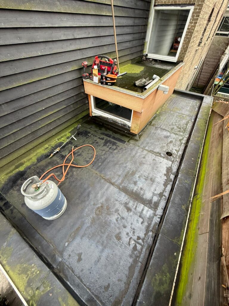 Nieuw overlaagd bitumen dak met aluminium daktrim op een aanbouw in Maassluis