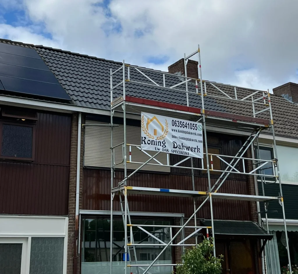 Nieuw antraciet pannendak op een rijwoning in Maassluis, geplaatst door Koning Dakwerk met steiger aan de gevel